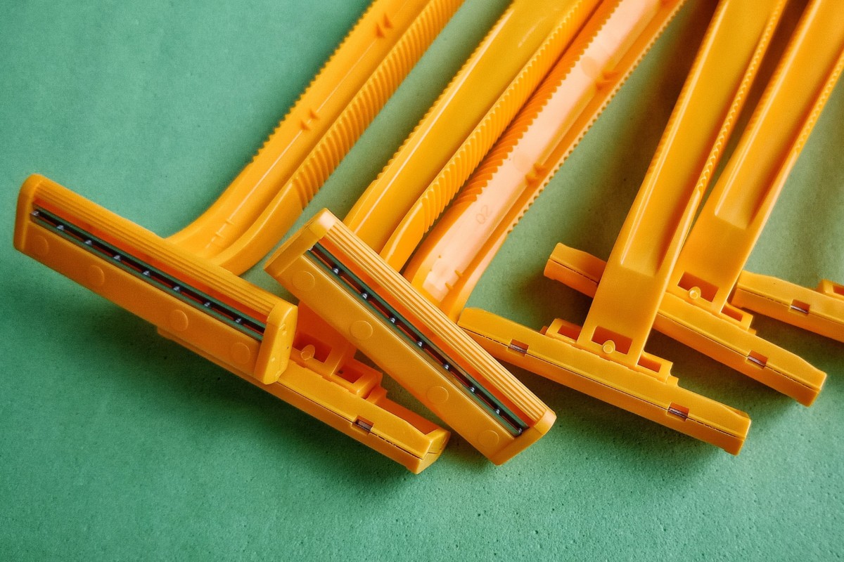 Orange disposable razor blades on a green background.