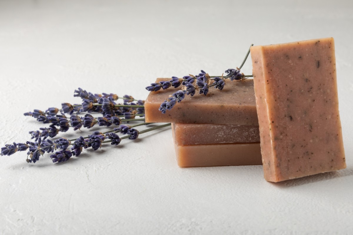 Bars of homemade lavender soap with sprigs of lavender lying next to them.