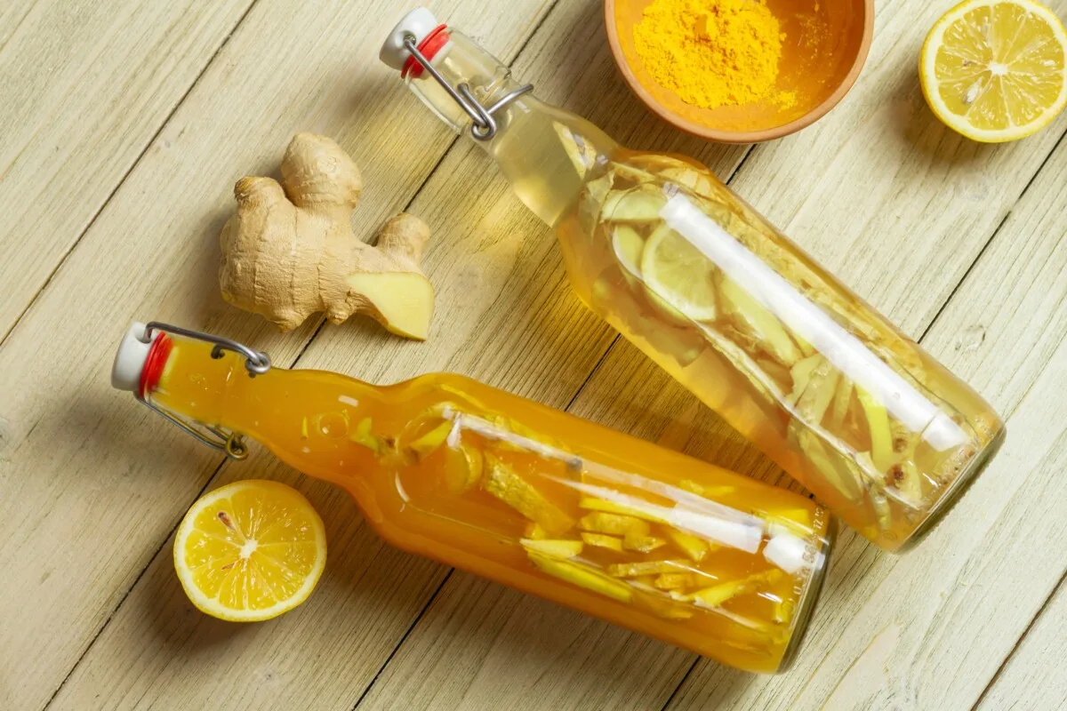 Two bottles of kombucha with ginger and lemon slices in them. 