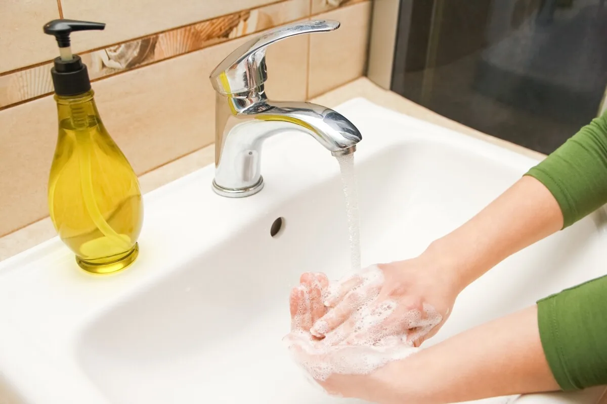 Person washing their hands at a sink. 