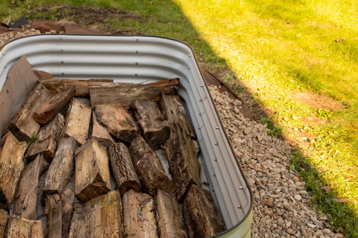 Old firewood in the bottom of a raised bed