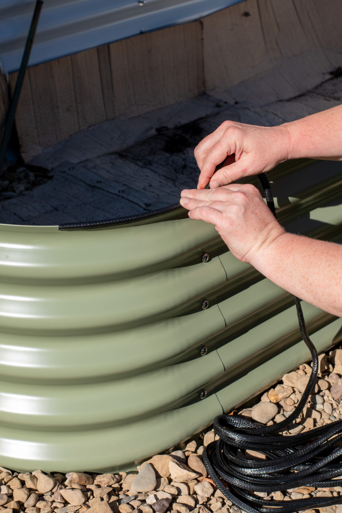 Woman adding rubberized edging to a raised bed