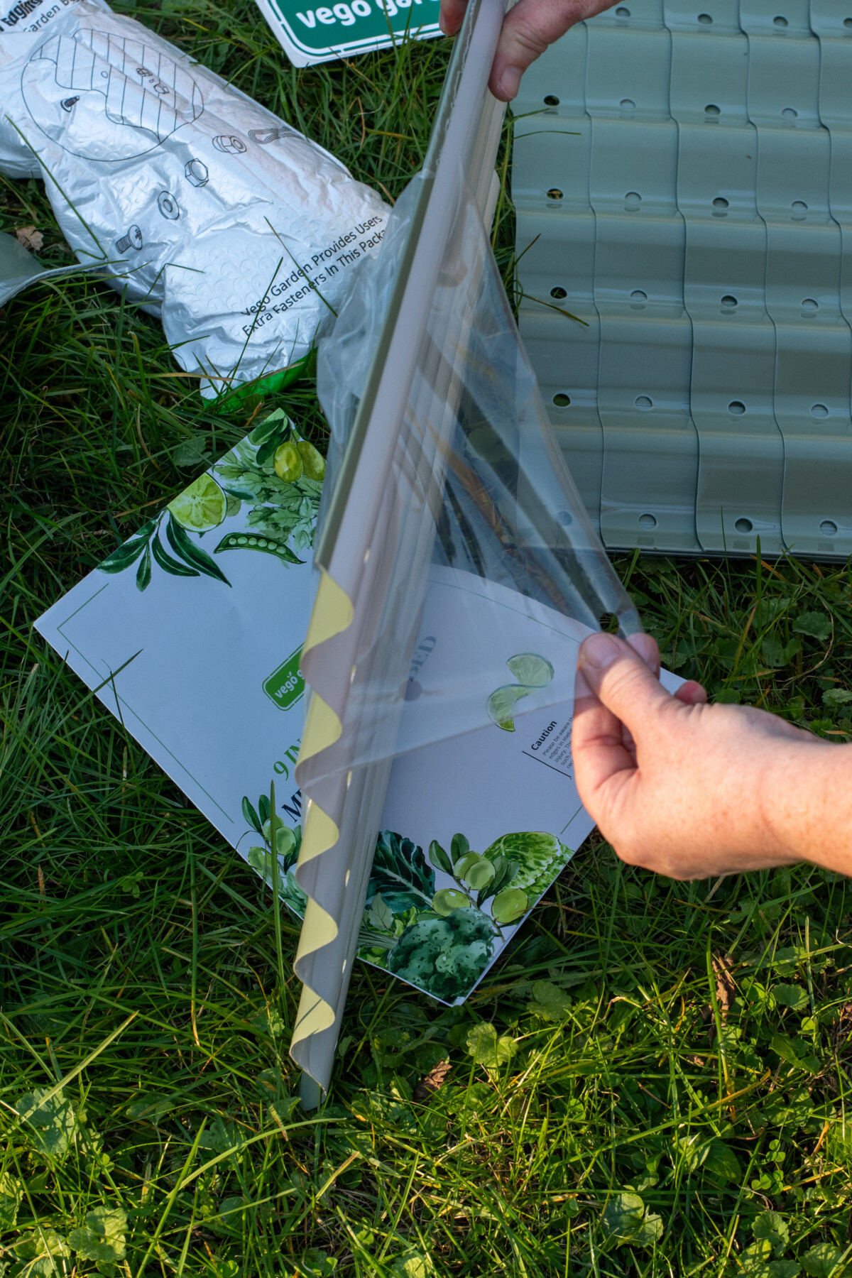 woman's hand pulling cling film from raised bed panel