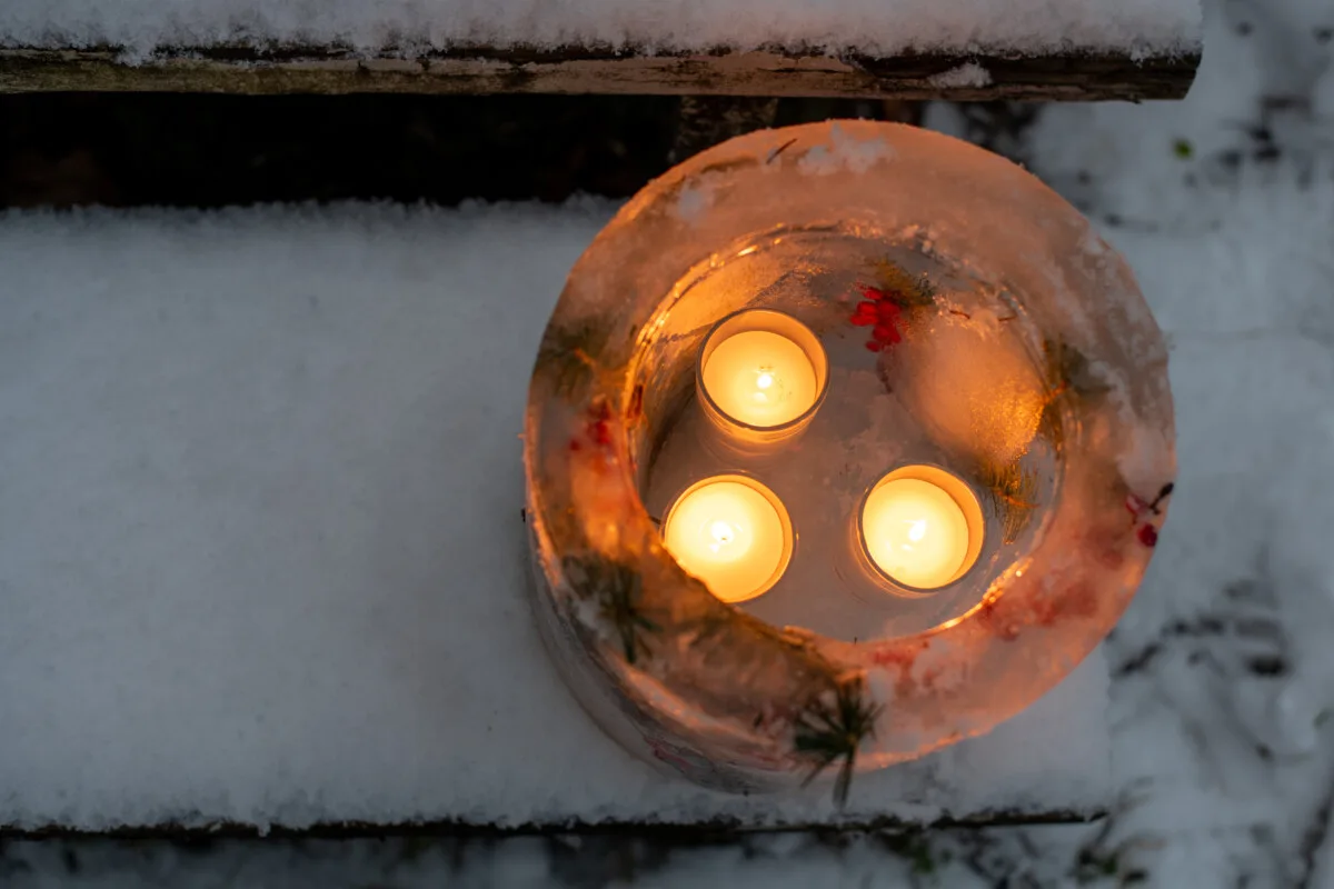 Three votive candles burning inside an ice luminary