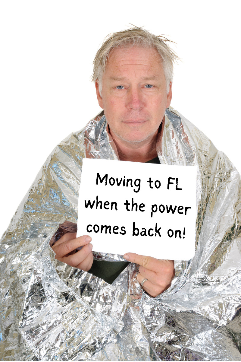 Man wearing mylar blanket with sign that reads, "Moving to FL when the power comes back on!"