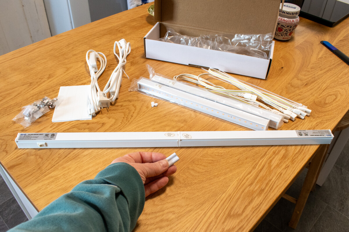 woman's hand holding an adapter to connect grow lights together. 